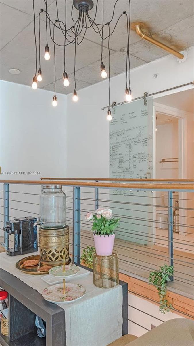 Exposed concrete ceiling with industrial chandelier, metal horizontal railing system with wood handrail, and frosted glass sliding door