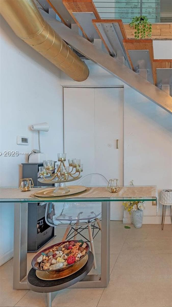 Open-riser staircase featuring metal stringers and wood treads with cable railing, complemented by industrial-style exposed metallic ductwork and polished concrete-style flooring
