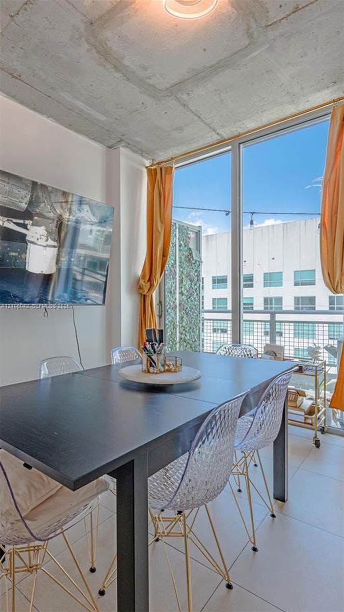 Industrial-style exposed concrete ceiling featuring floor-to-ceiling windows and large-format tile flooring
