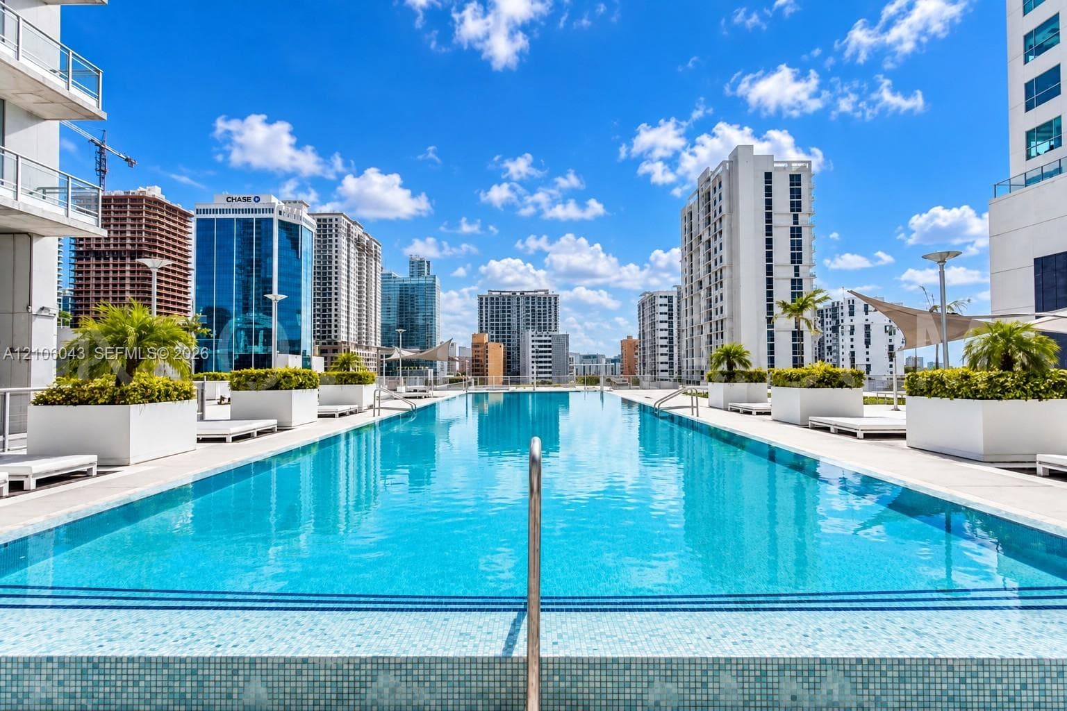 Rooftop swimming pool featuring a mosaic-tile finish, a stainless steel handrail, and built-in concrete planters