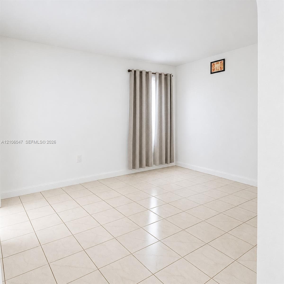 Neutral interior space featuring large-format tile flooring, white wall finishes, and a window with a curtain rod installation