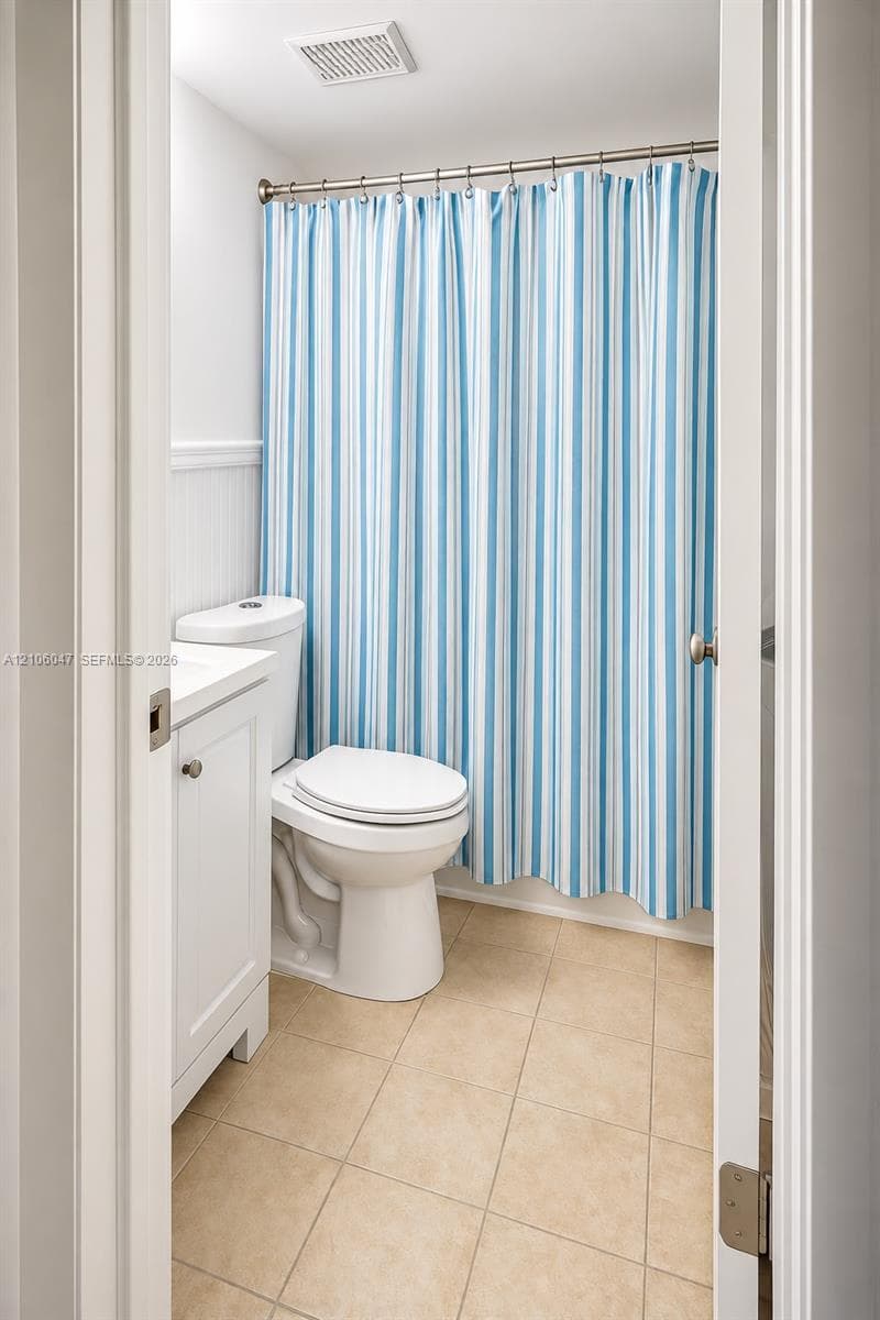 Bathroom featuring a white vanity cabinet, ceramic tile flooring, and wall-mounted beadboard wainscoting