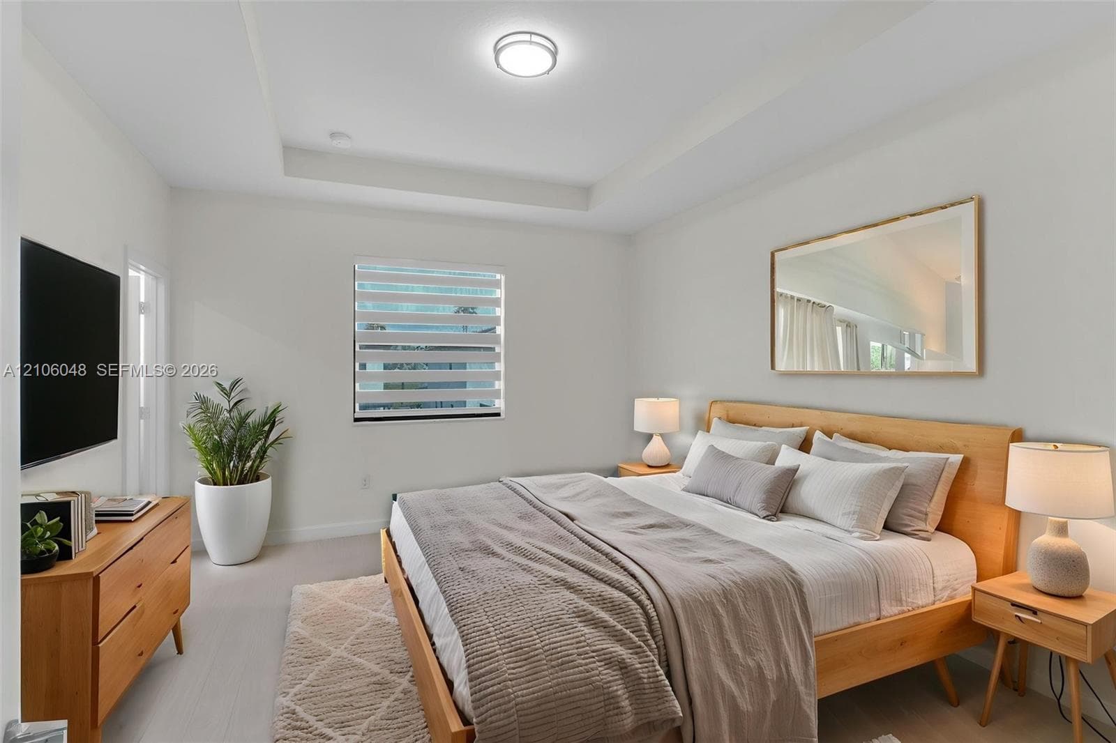 Tray ceiling, neutral walls, light-toned flooring, and window with adjustable light-filtering shade