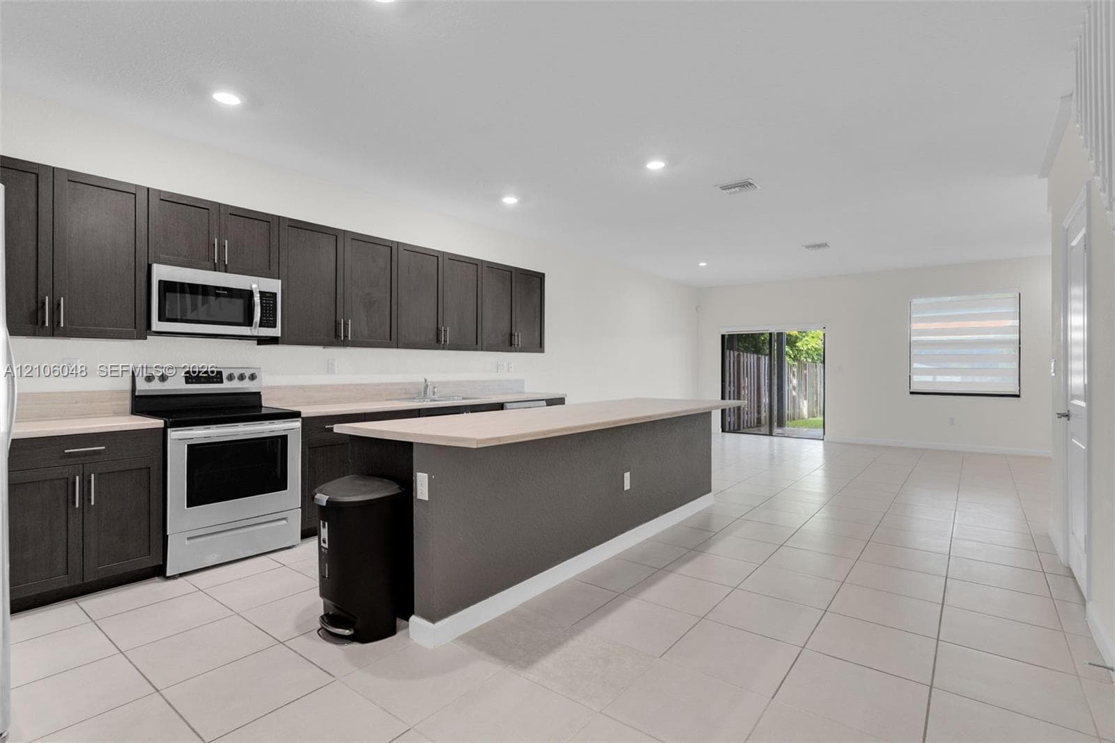 Kitchen featuring dark cabinetry, expansive breakfast bar, recessed lighting, and tile flooring