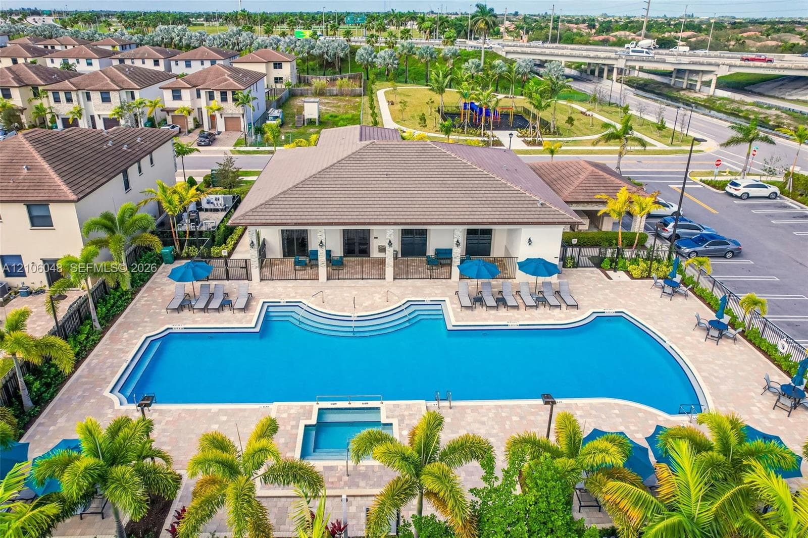 Resort-style resort amenity featuring a resort-style zero-entry pool with curved architectural design, spa, and integrated sun shelf