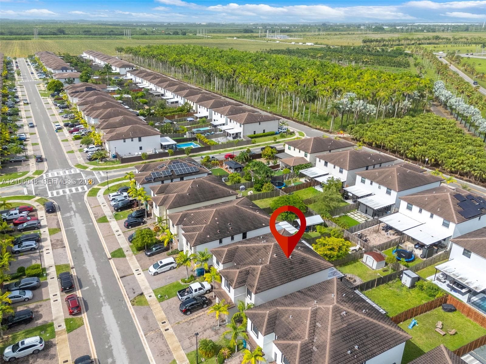 Aerial perspective of a multi-unit residential community featuring hipped roof structures, paved street access, and fenced yard spaces