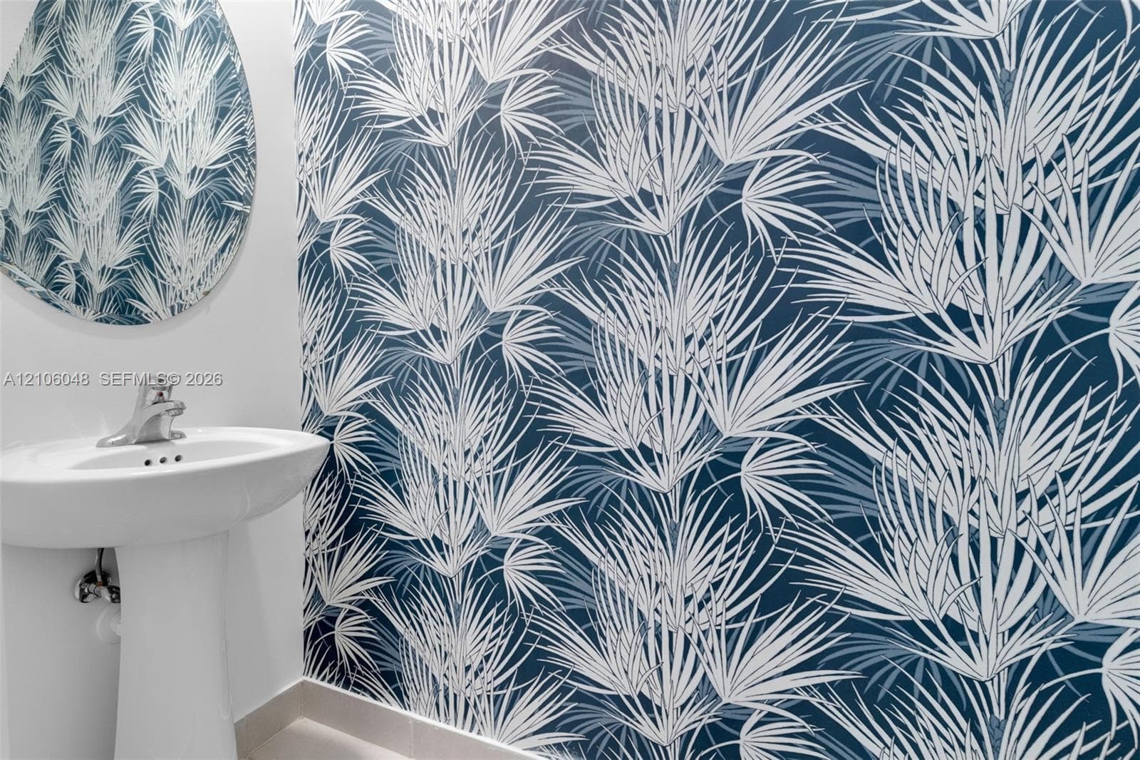 Botanical-print wallpaper, pedestal sink with polished chrome hardware, and circular wall mirror