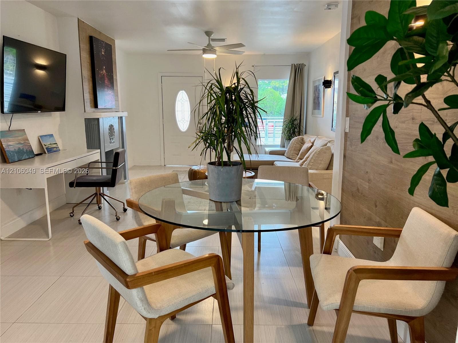 Light-toned tile flooring, wood-finish wall paneling, ceiling-mounted paddle fan, and an architectural fireplace surround