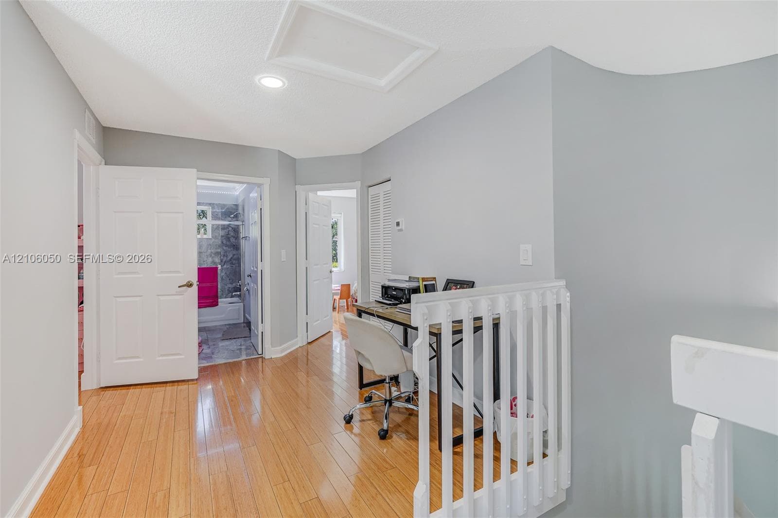 Interior hallway featuring wood-finish flooring, white paneled doors, recessed lighting, and a white vertical balustrade