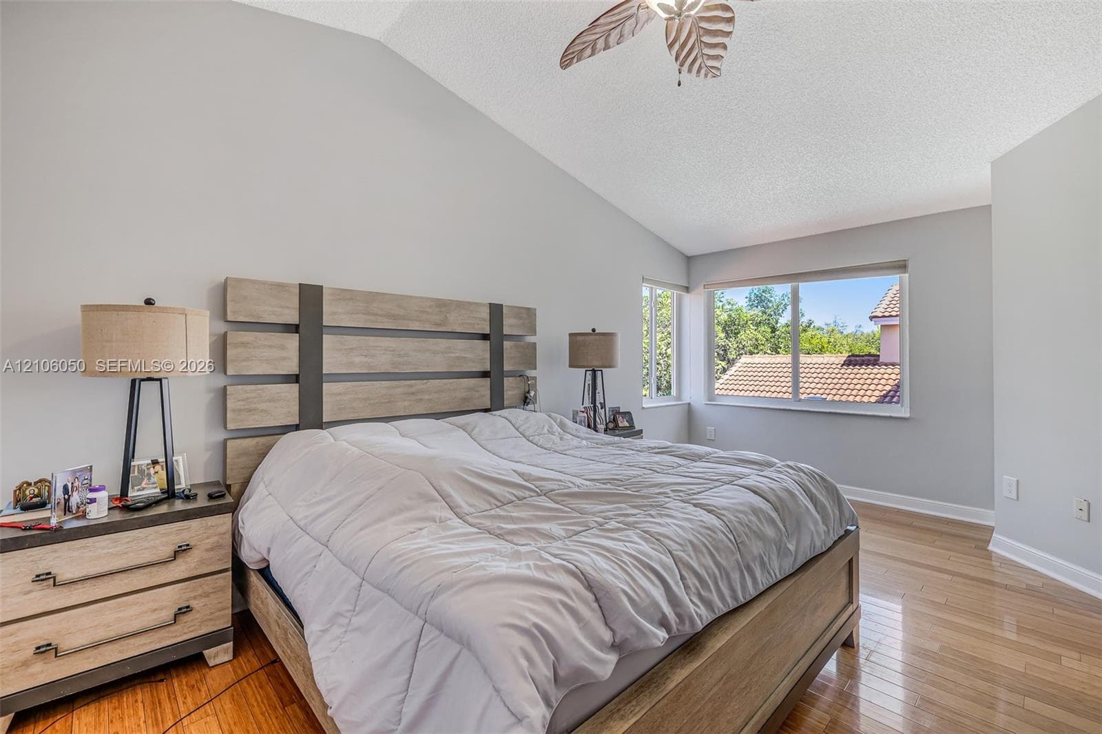 Vaulted ceiling with a central fan, light-toned wood-finish flooring, and large sliding windows