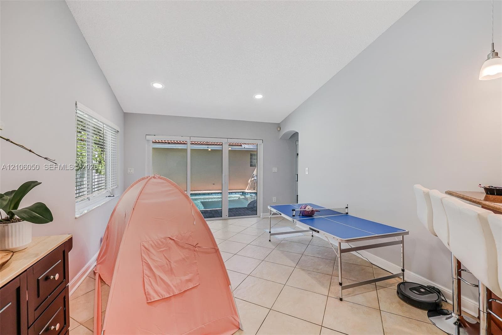 Vaulted ceilings with recessed lighting, tile flooring, sliding glass doors, and a built-in wet bar with cabinetry
