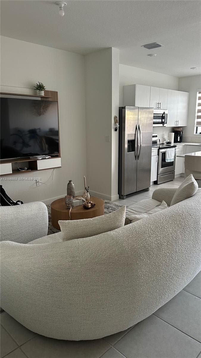 Kitchen featuring white cabinetry, stainless steel refrigerator, and stainless steel range
