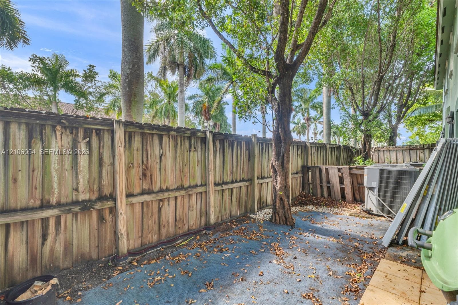 Exterior side yard featuring a vertical wood privacy fence and mature landscaping