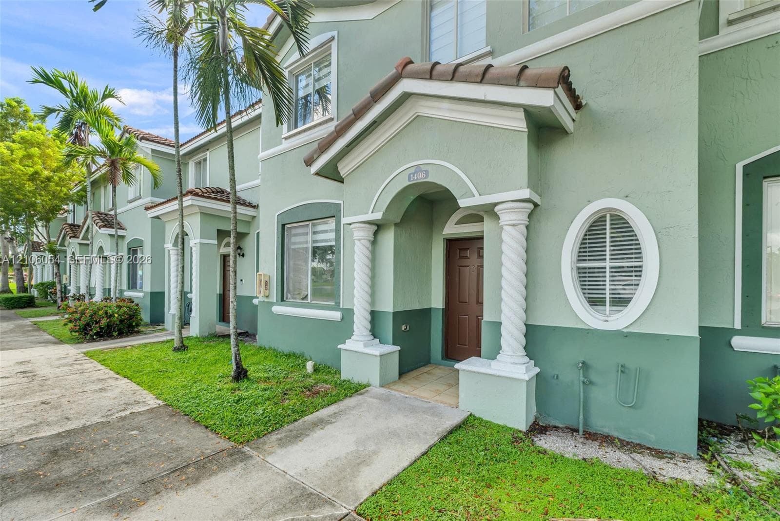 Stucco exterior featuring dual-tone paint, a covered entrance with spiral columns, and a decorative oval window