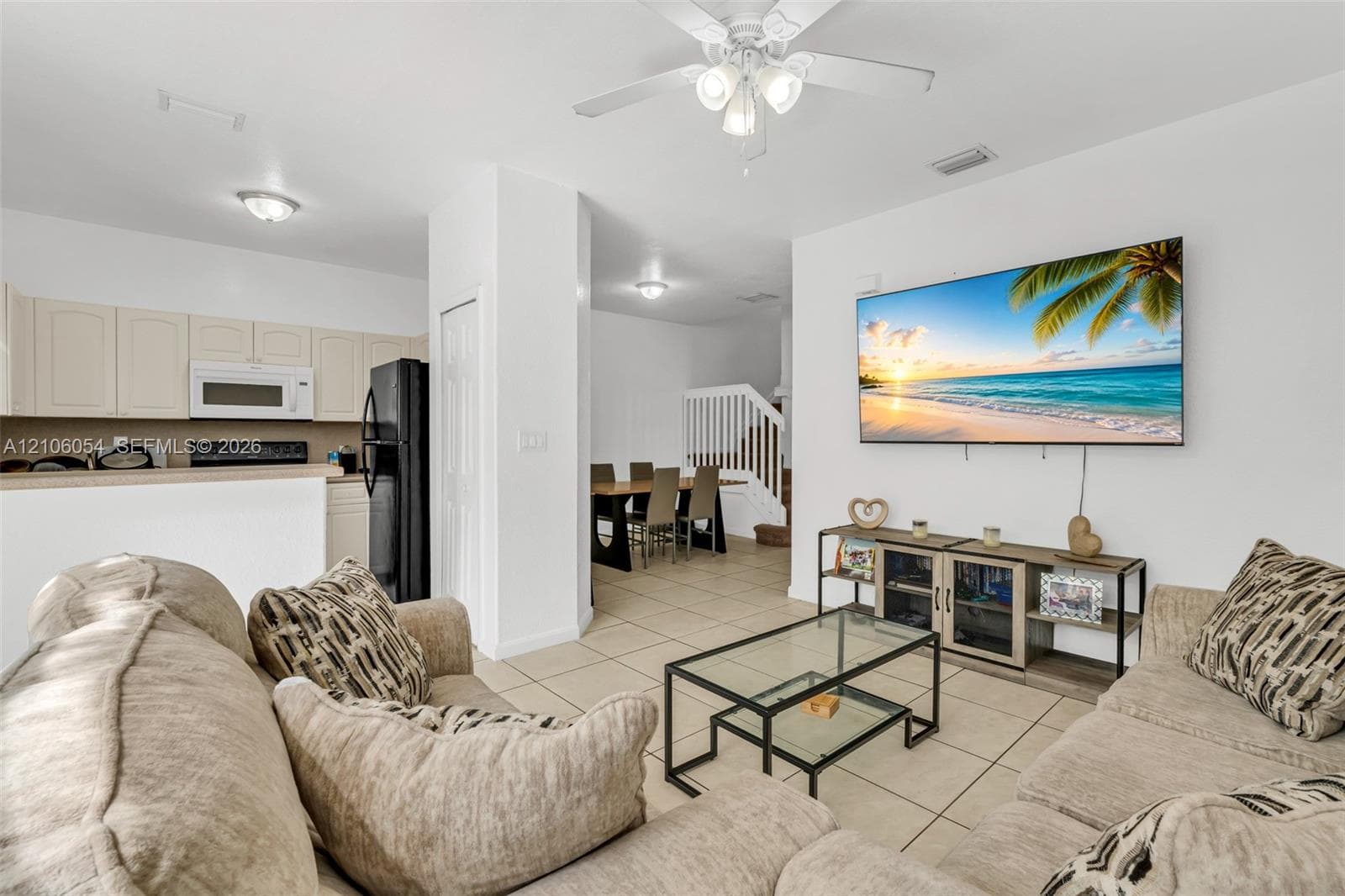 Open-concept living space featuring ceramic tile flooring, neutral wall finishes, a ceiling fan, and built-in cabinetry