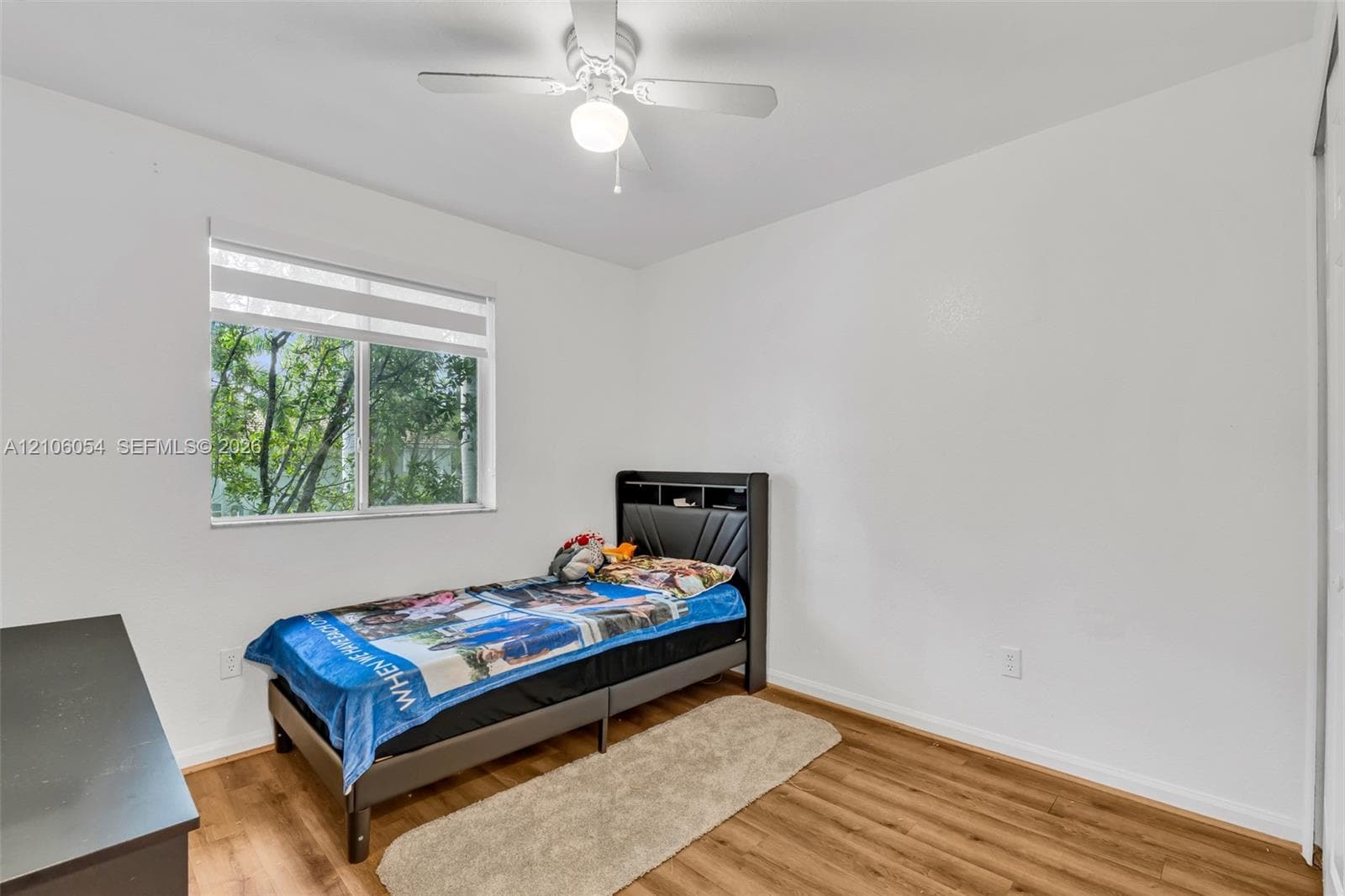 Wood-finish flooring, multi-pane window, and white ceiling fan with integrated lighting