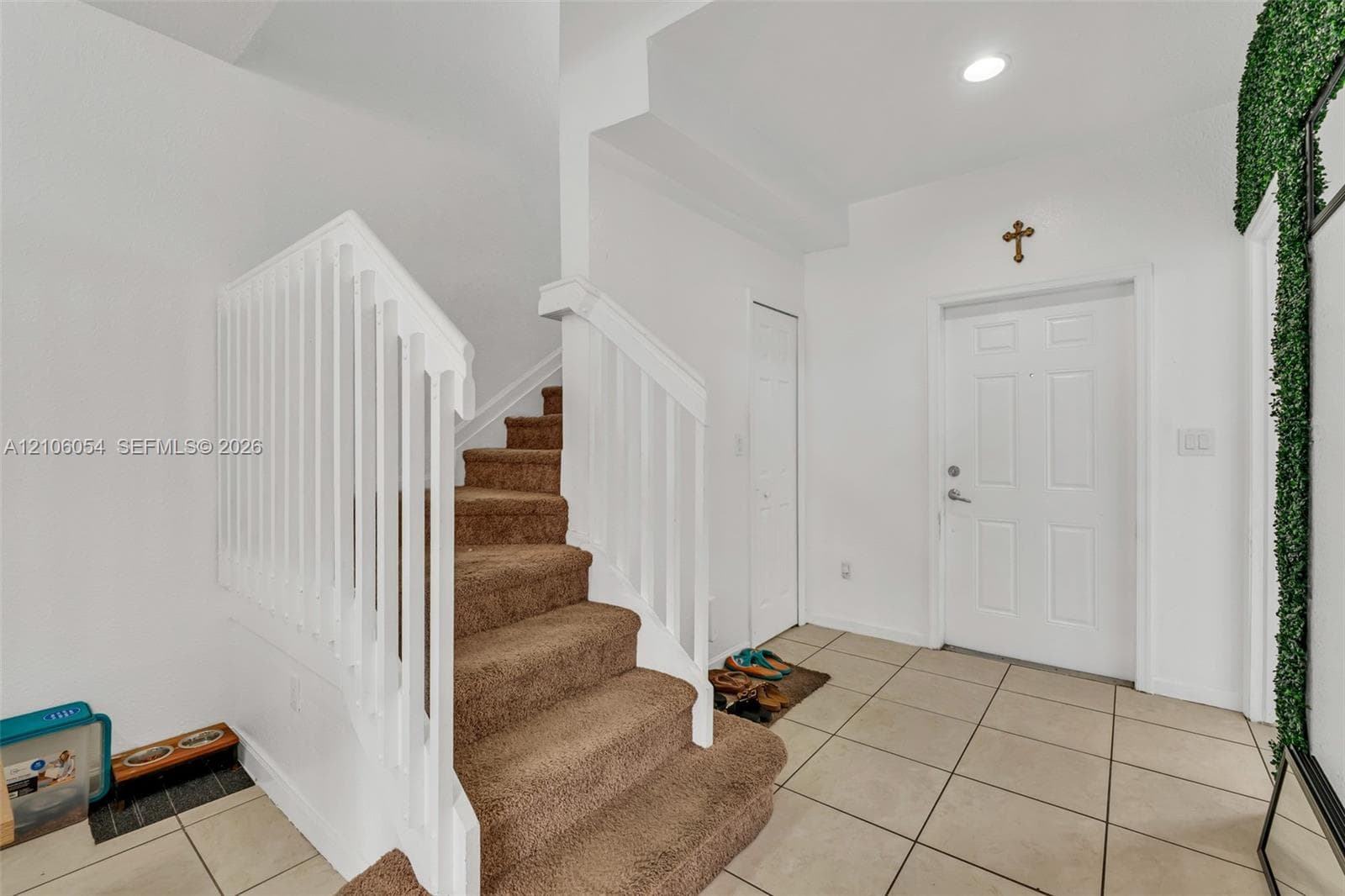 Entryway featuring ceramic tile flooring, a staircase with carpeted treads, and a white picket-style balustrade