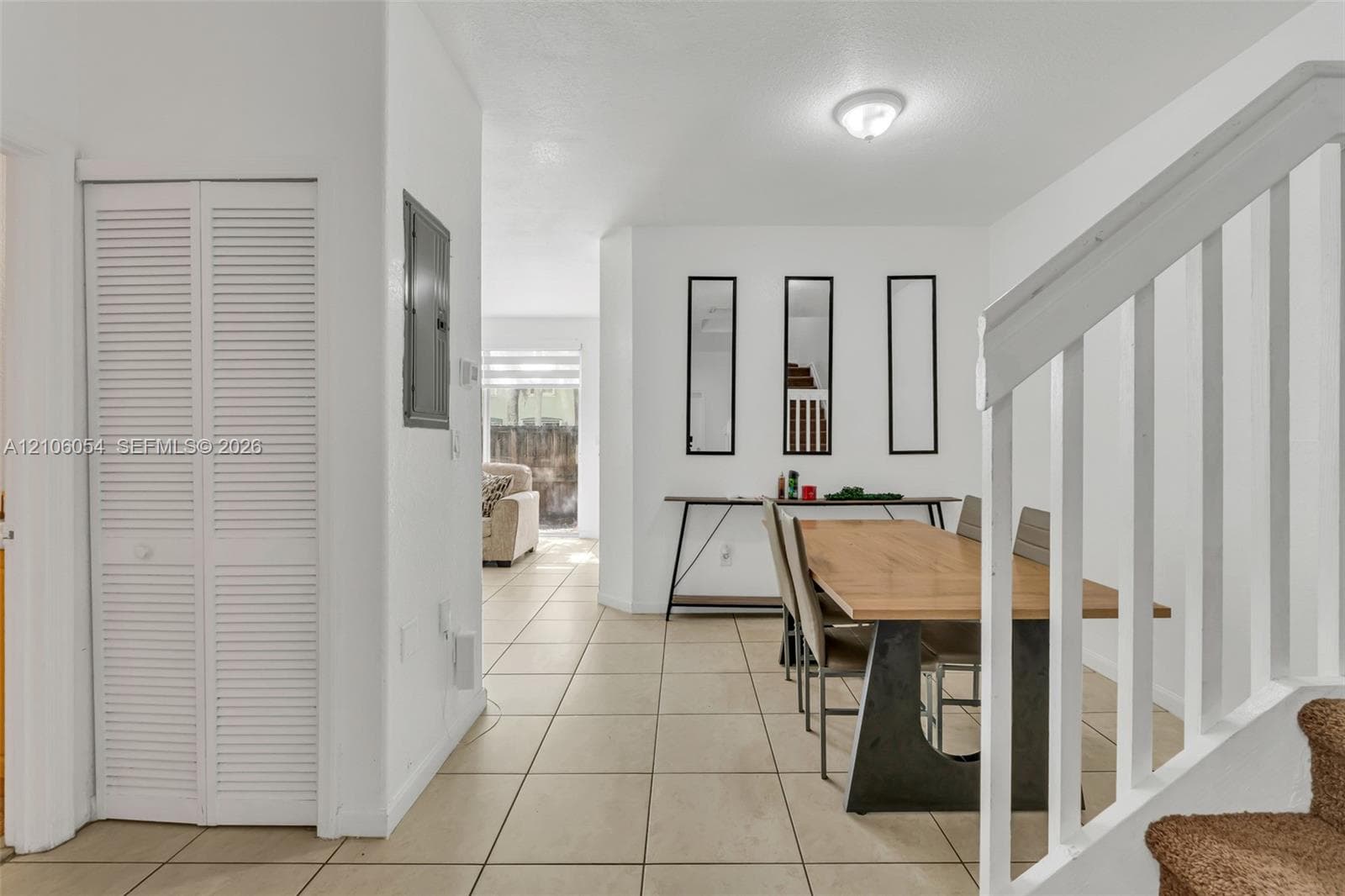 Interior space featuring tile flooring, louvered closet doors, and a staircase with a white balustrade