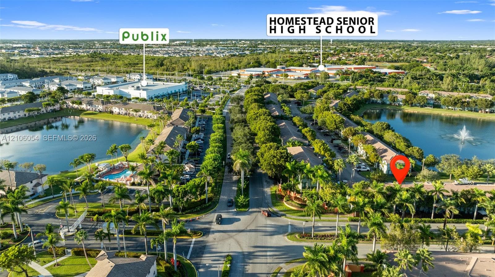 Aerial perspective of a multi-unit residential community featuring waterfront locations, mature landscaping, palm trees, and an on-site swimming pool