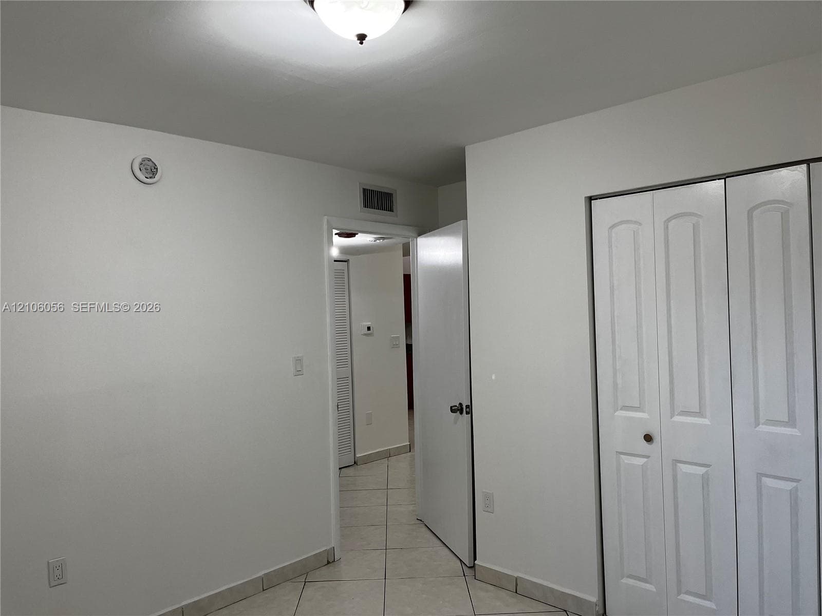 Interior space featuring tile flooring, neutral wall tones, bi-fold closet doors, and overhead flush-mount lighting