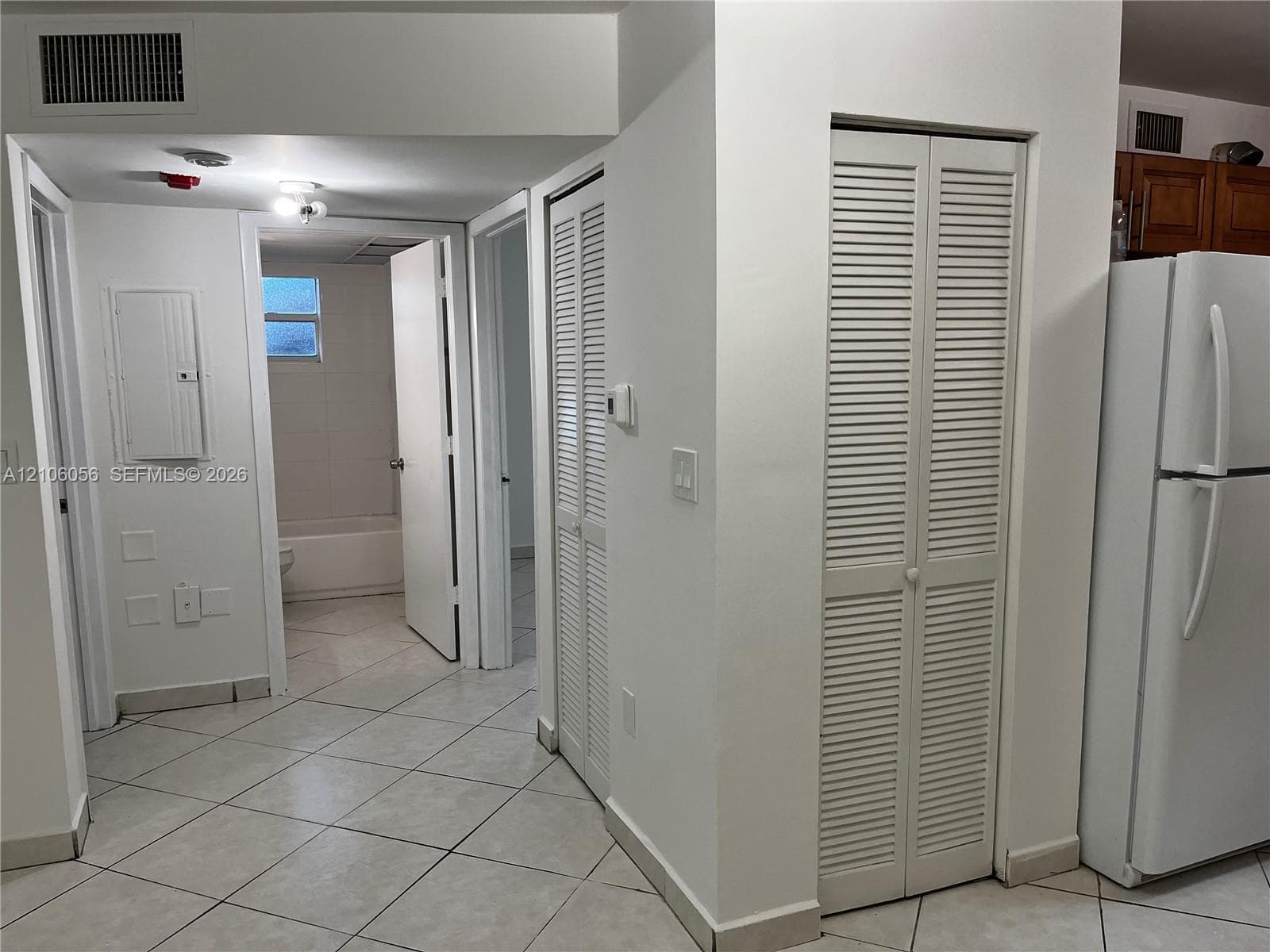 Interior hallway featuring neutral ceramic tile flooring and two sets of louvered-door closets