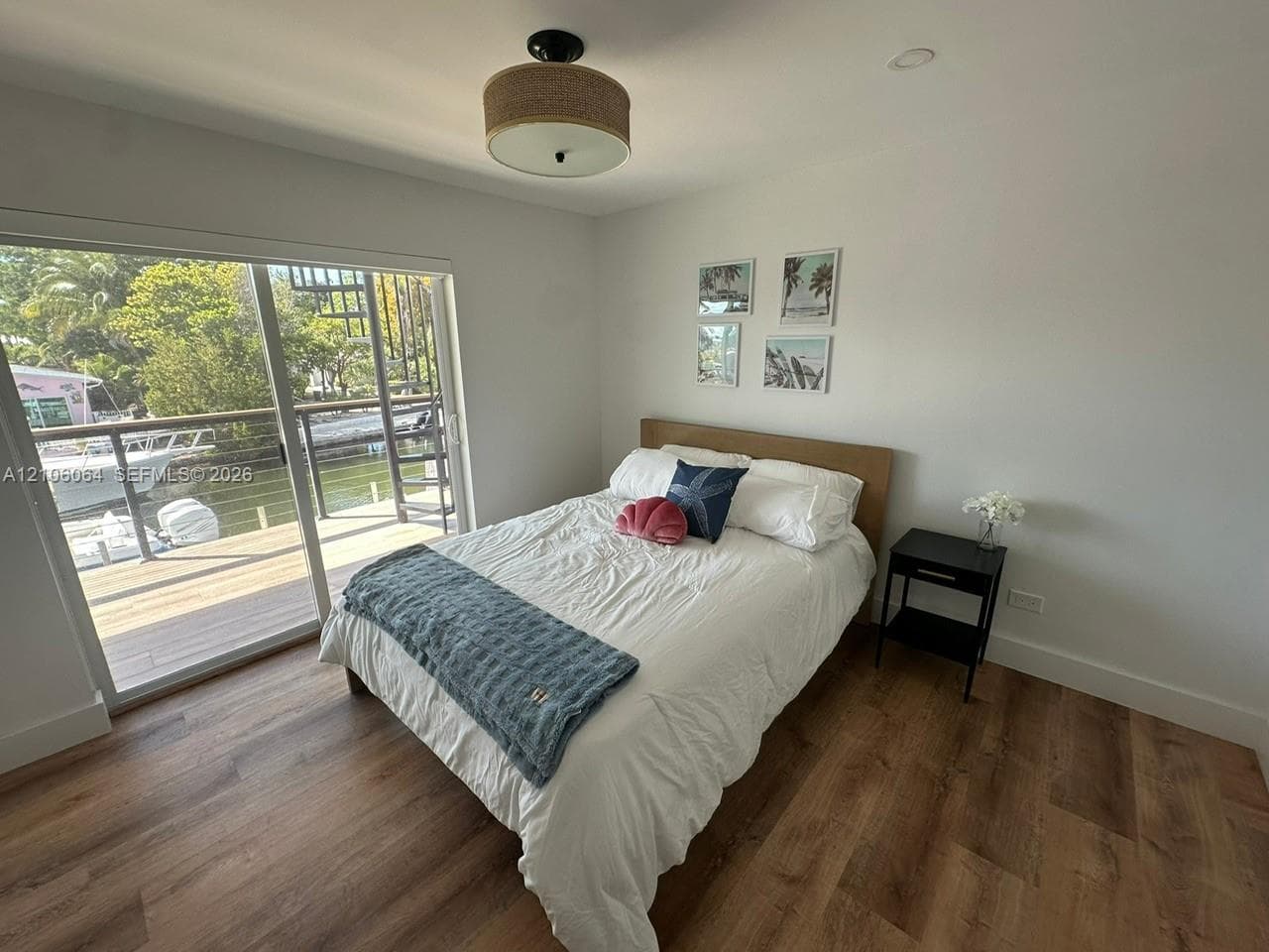 Sliding glass door opening to a deck, wood-finish flooring, and a drum-style ceiling light fixture