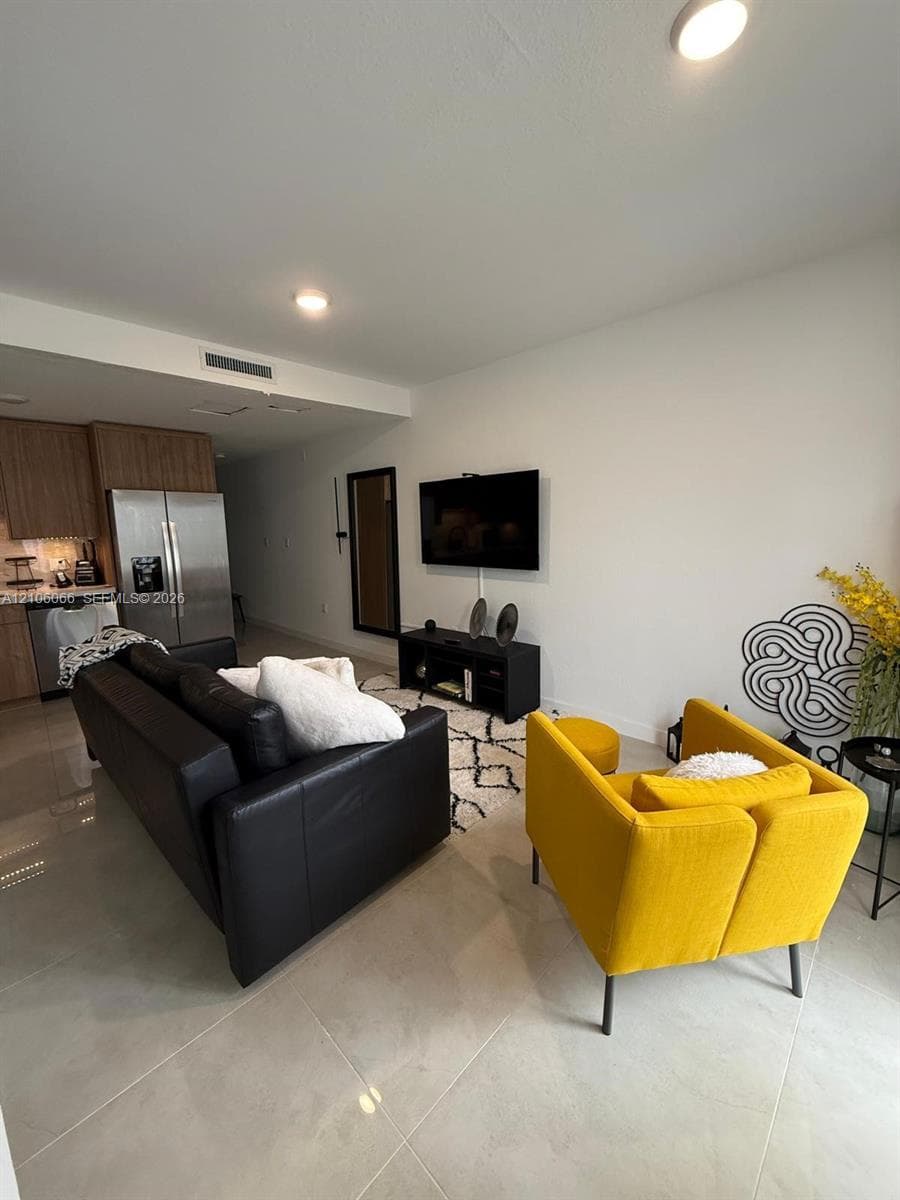 Large-format tile flooring, recessed ceiling lighting, and stainless steel kitchen appliances