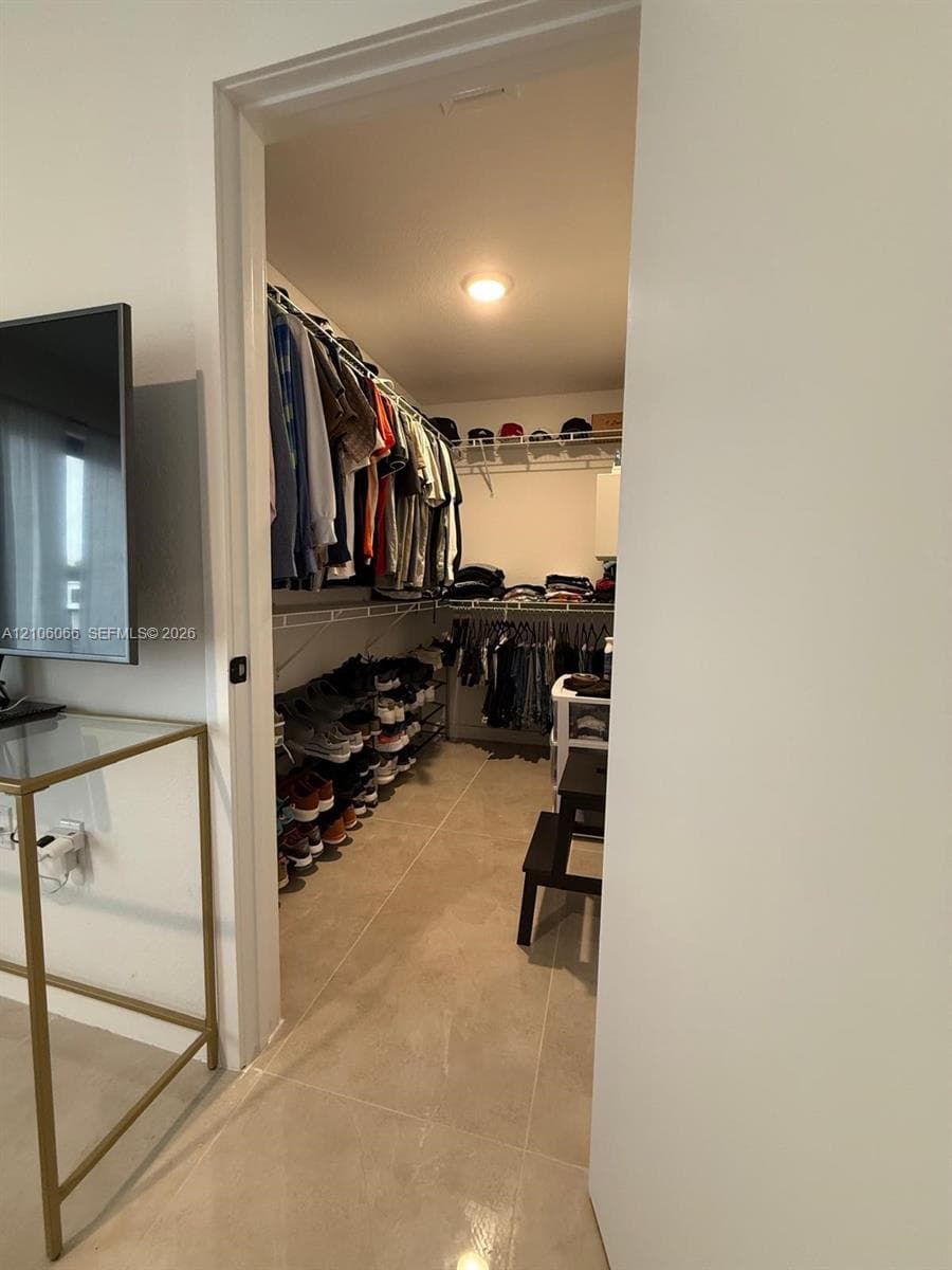 Walk-in closet featuring floor-to-ceiling shelving, tiered wire racking, and neutral tile flooring