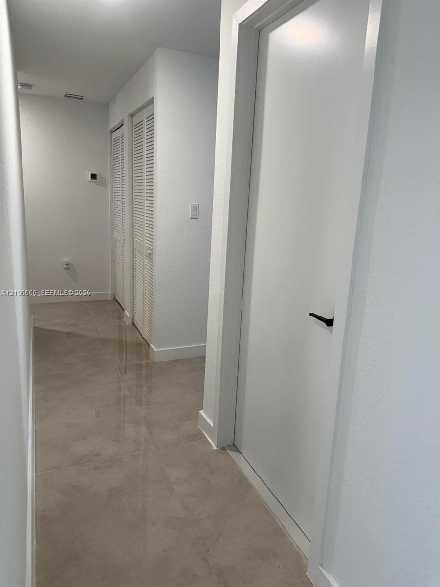 Large-format tile flooring, crisp white interior finishes, and dual louvered-panel closets featuring matte black door hardware