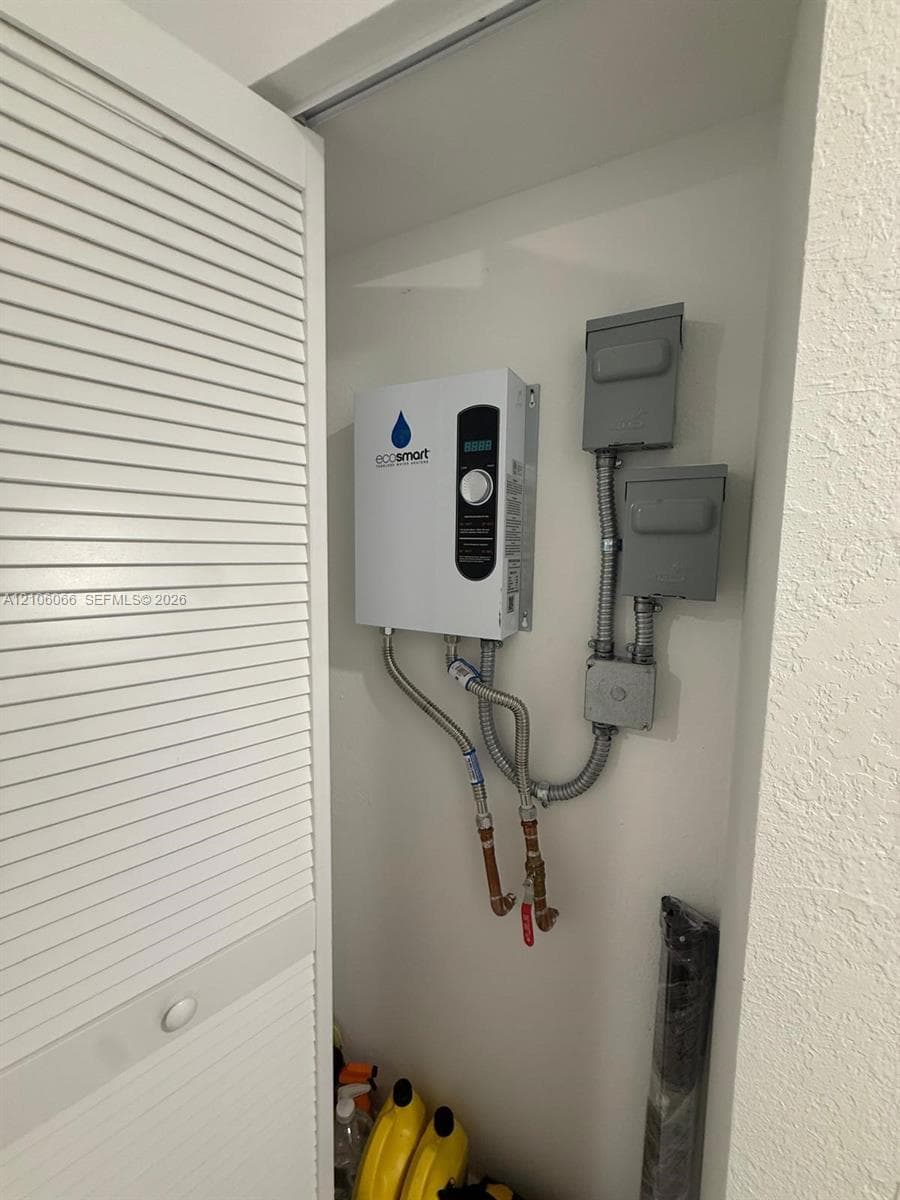 Tankless electric water heater featuring a digital temperature control interface, wall-mounted configuration, and metal conduit electrical housing