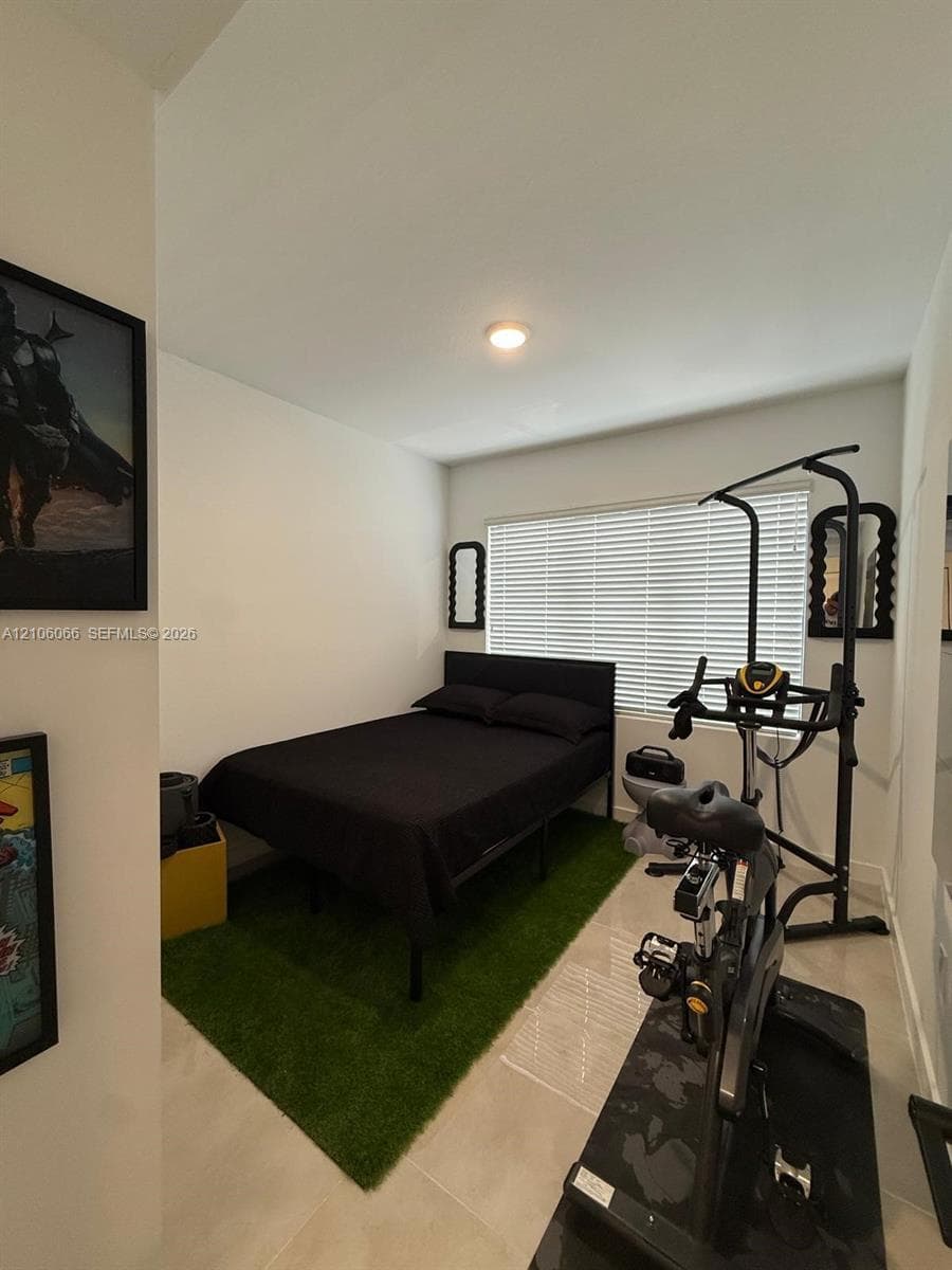 Neutral-toned walls, large window with horizontal blinds, flush-mount ceiling lighting, and light-colored tile flooring