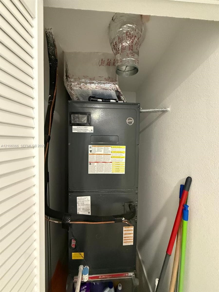 Vertical HVAC unit housed in an enclosed utility closet with louvered door access