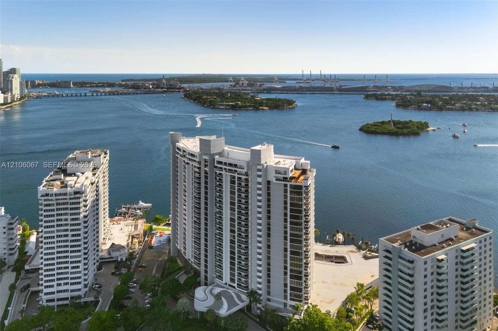 High-rise residential building featuring exterior balconies, a circular porte-cochère, and coastal surroundings