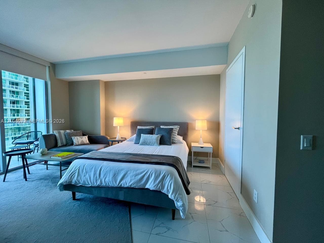 Floor-to-ceiling windows, polished stone-finish tile flooring, and neutral wall tones