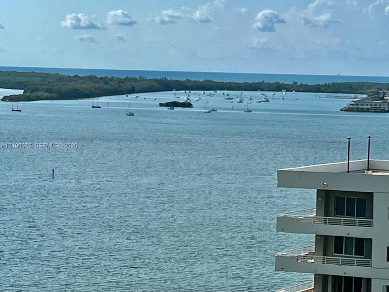 Expansive coastal scenery featuring open water, a barrier island, and multiple tiered balconies with horizontal railings