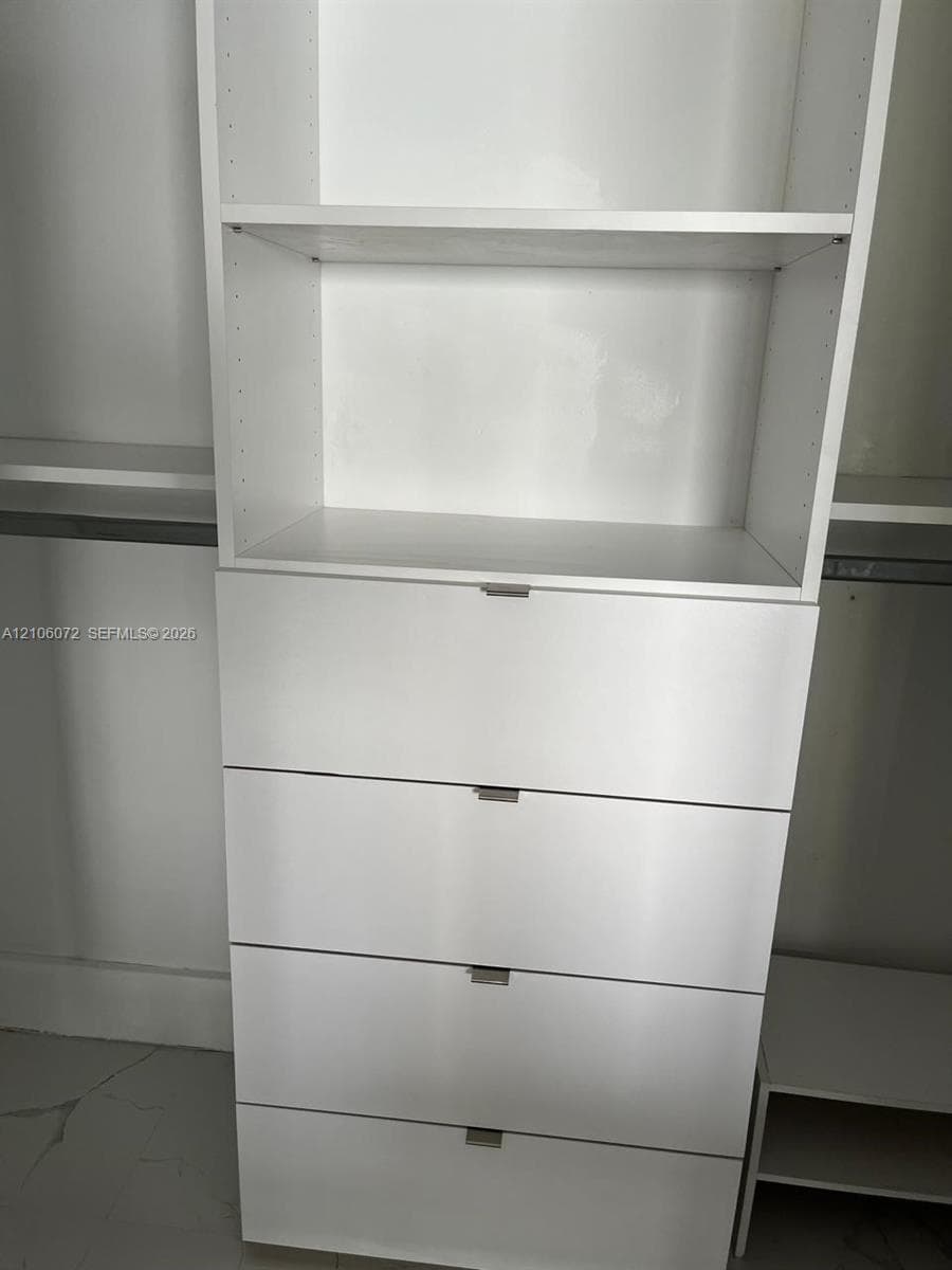 Built-in closet organizer featuring white laminate cabinetry, four soft-close drawers, adjustable shelving, and integrated metal clothing rods
