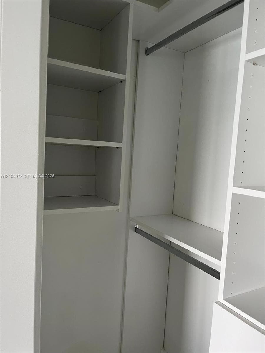 Custom reach-in closet featuring white built-in shelving, adjustable cubbies, and dual metal hanging rods