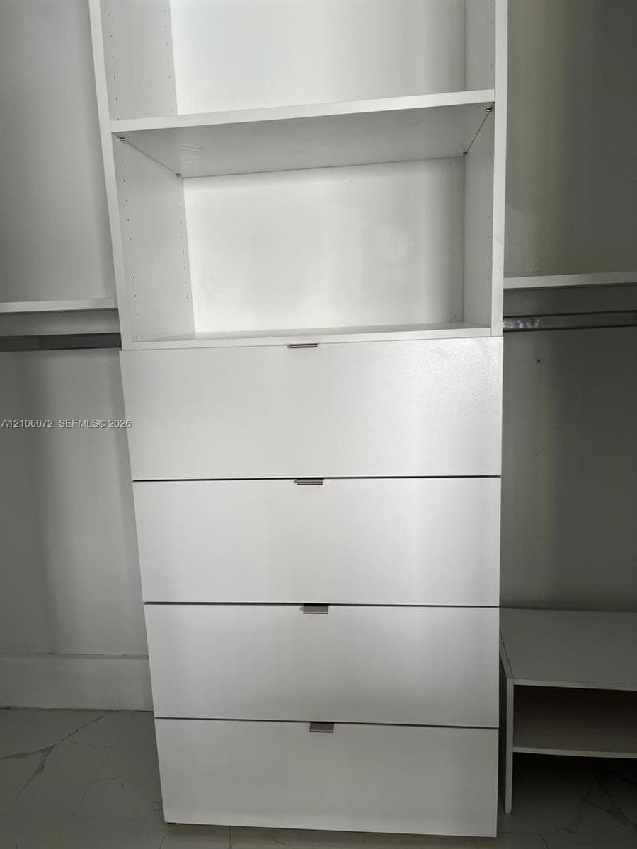 Built-in closet system featuring white cabinetry, four soft-close storage drawers with horizontal pulls, adjustable shelving, and integrated metal garment rods
