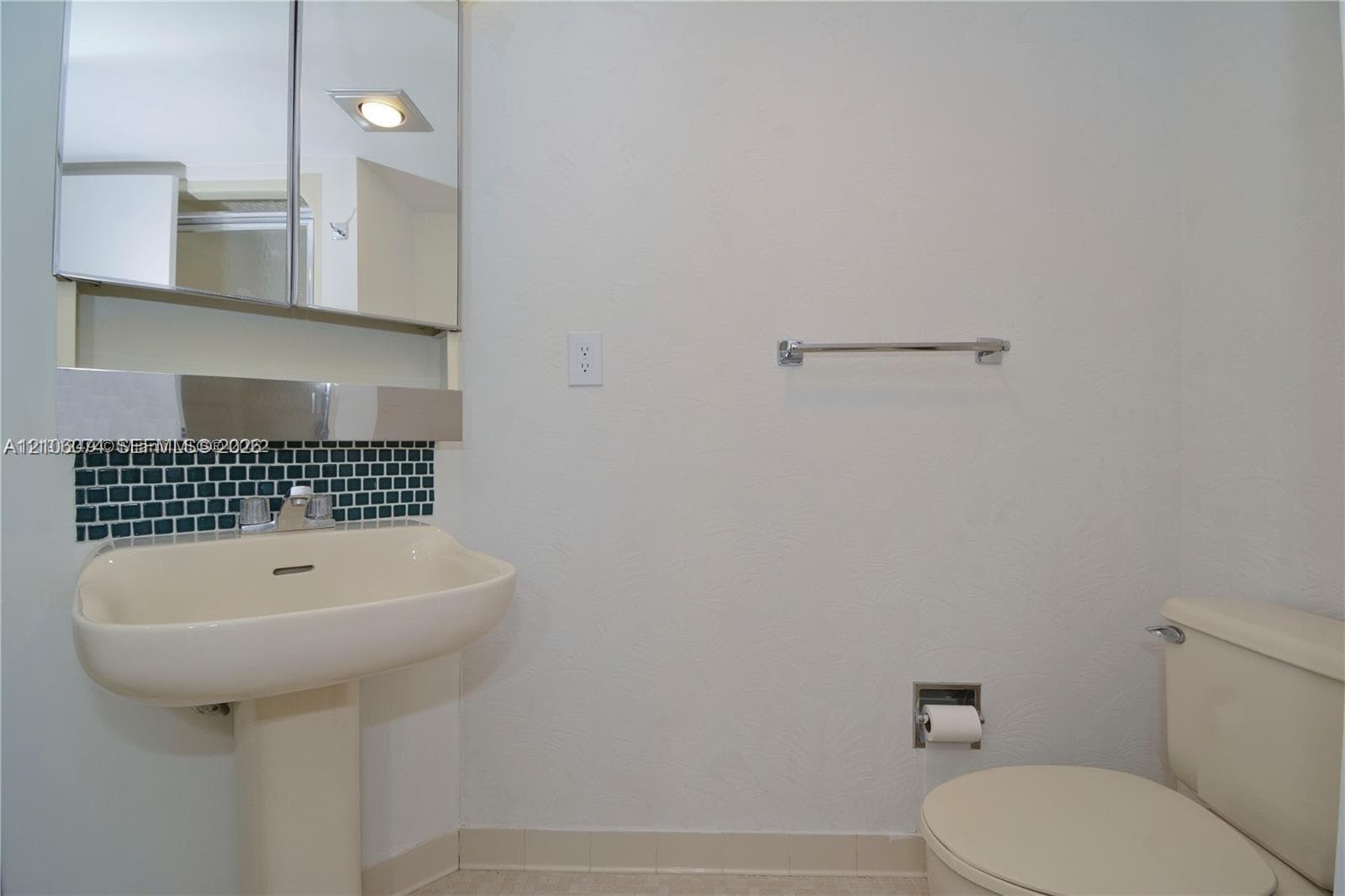 2nd Bath with Pedestal sink & shower with a single-handle faucet, mirrored medicine cabinet, geometric mosaic tile backsplash, and polished chrome hardware