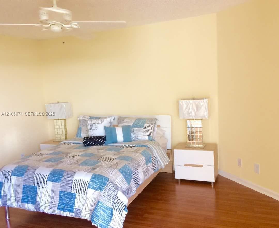 Room interior featuring wood-finish flooring and a ceiling-mounted fan with integrated lighting