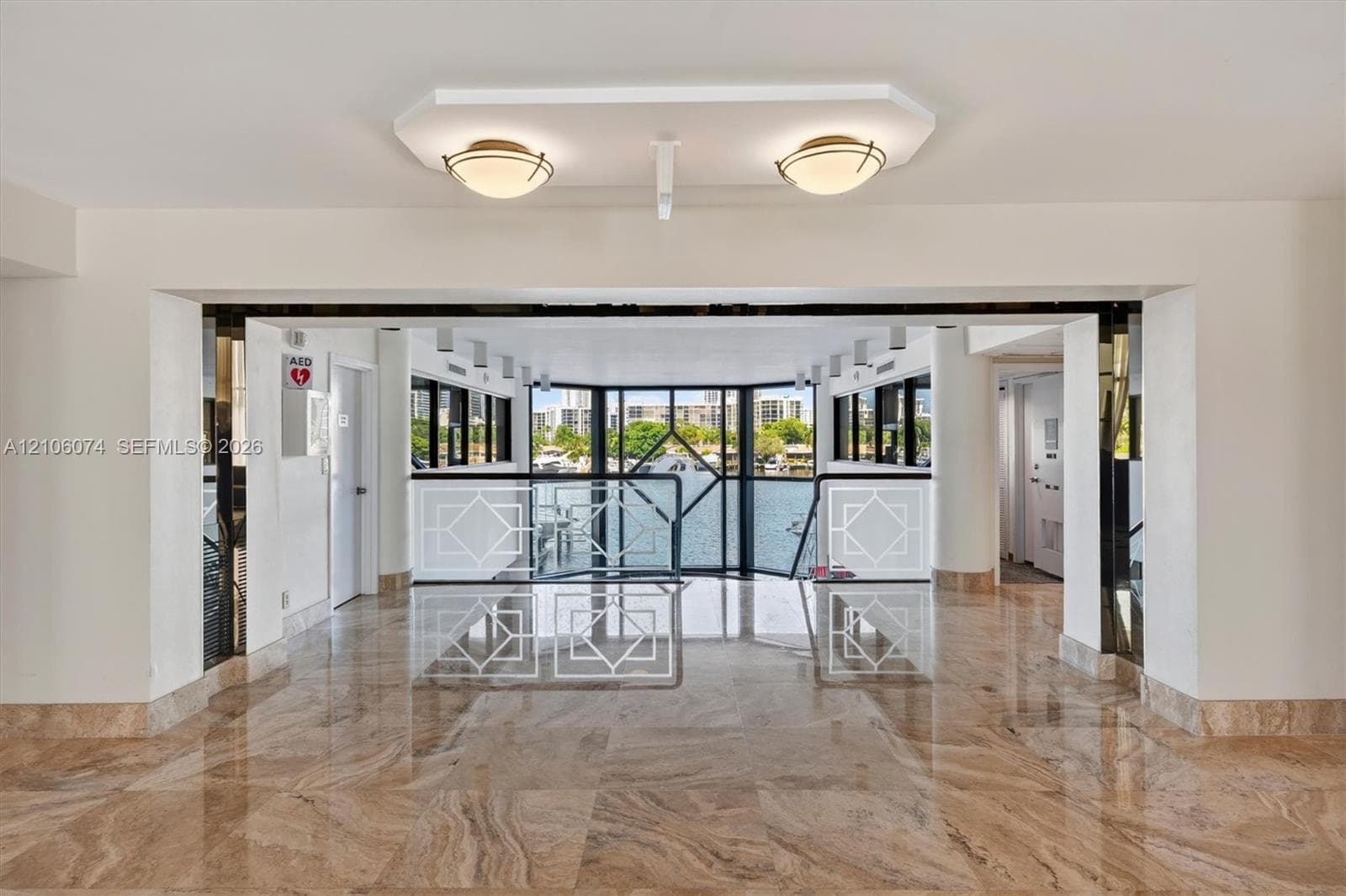 Polished stone flooring, expansive glass window wall, geometric metal railings, dual recessed ceiling fixtures, and structural columns