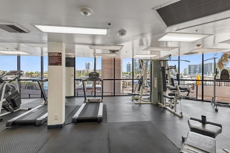 Fitness facility featuring floor-to-ceiling windows, rubberized flooring, and recessed lighting