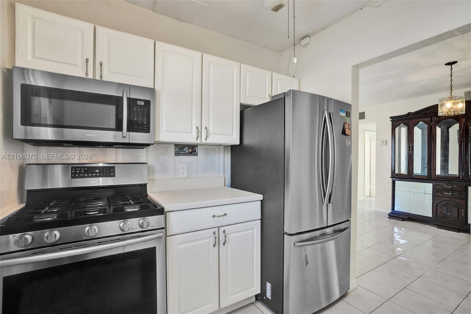 Kitchen featuring white cabinetry, stainless steel gas range, stainless steel microwave, and stainless steel refrigerator