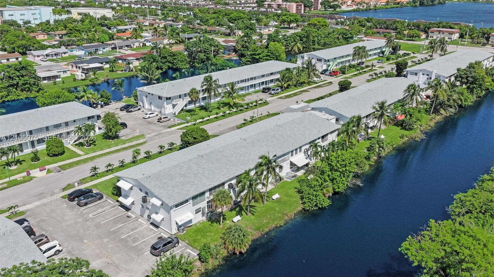 Multi-unit complex featuring exterior white siding, gabled rooflines, designated surface parking, and water frontage along a canal