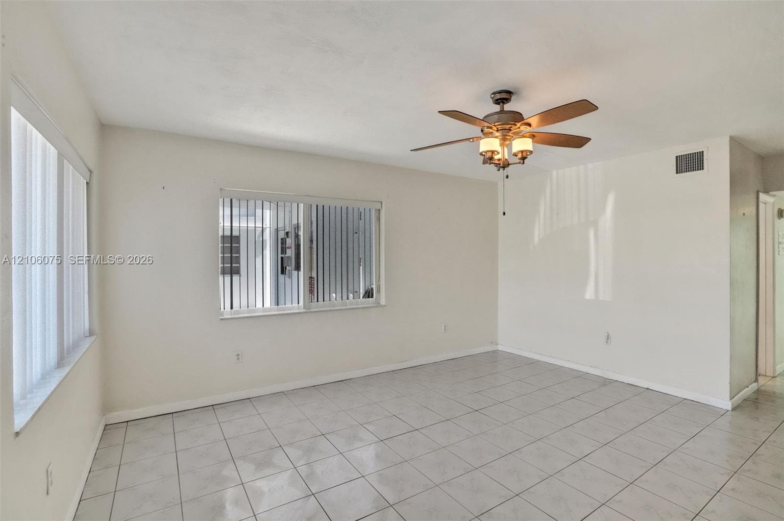 Ceramic tile flooring, multi-pane windows with vertical blinds, and a central ceiling fan with integrated lighting