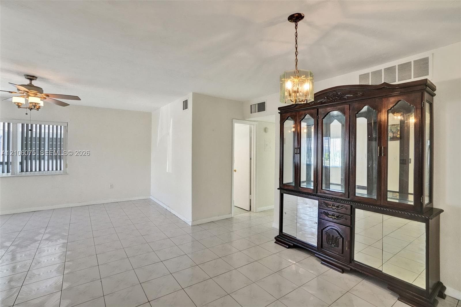 Neutral-toned tile flooring, built-in display cabinetry with glass paneling, multi-light hanging pendant fixture, and ceiling-mounted fan with integrated lighting