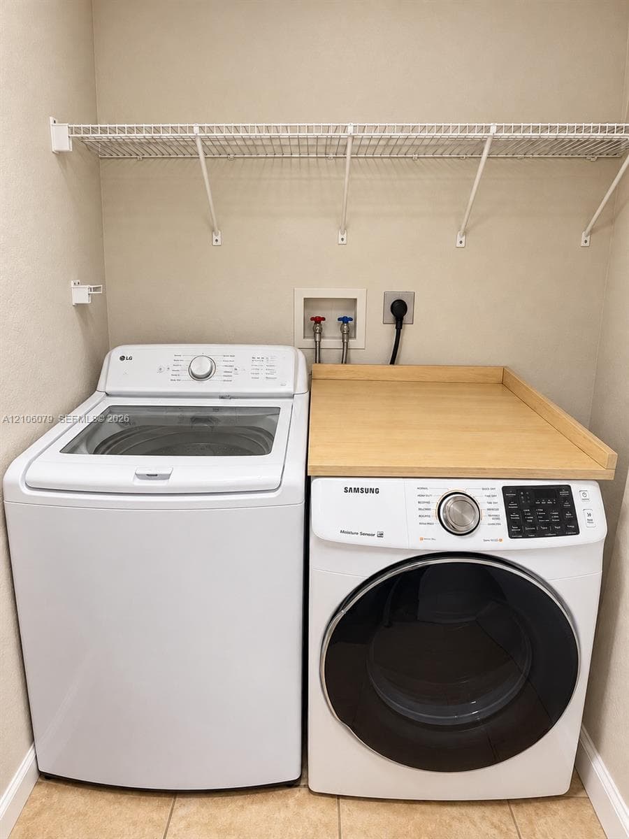 Laundry area featuring ceramic tile flooring, built-in wire shelving, and a custom wood-surface folding station