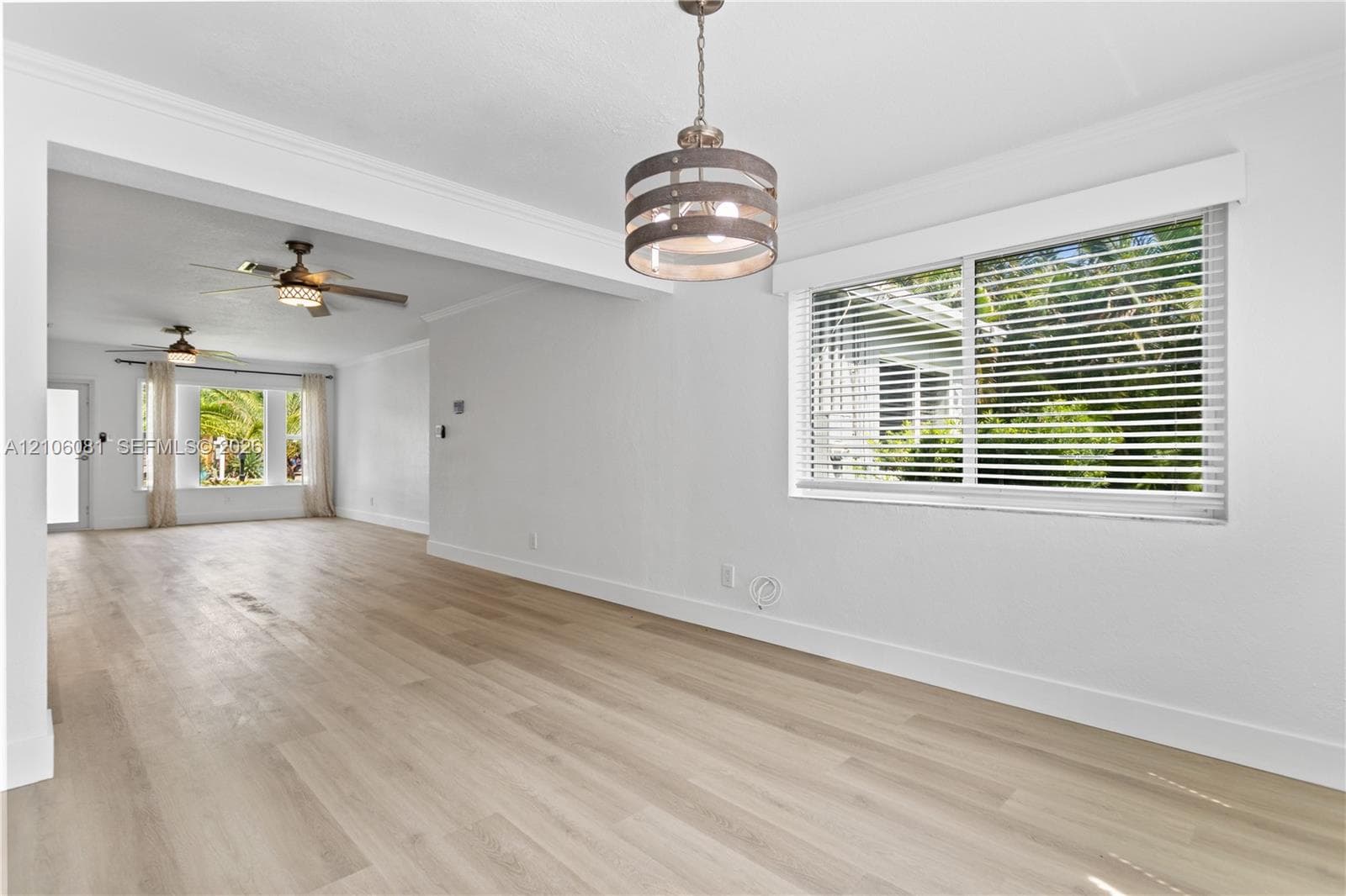 Wood-finish flooring, neutral walls, drum-style pendant lighting, and multiple ceiling fans