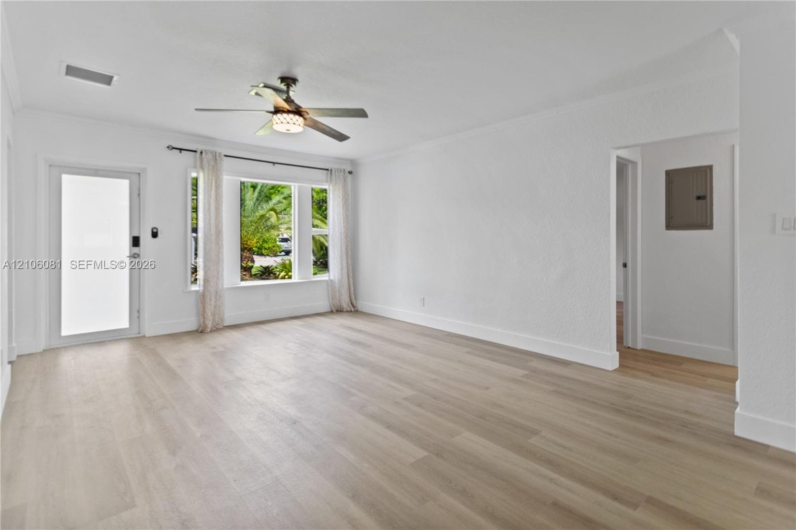 Interior space featuring wood-finish flooring, a multi-pane window, a glass-panel exterior door, and an overhead ceiling fan