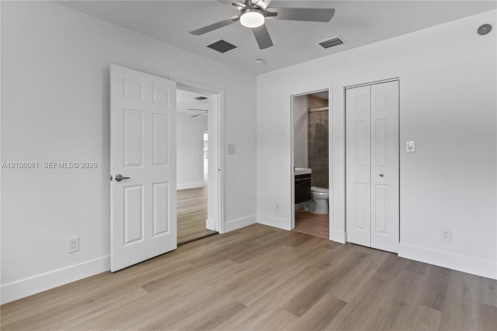 Room featuring wood-finish flooring, a ceiling fan with integrated lighting, dual-panel interior doors, and a bi-fold closet